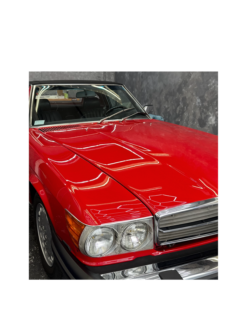 Reflections across the red bonnet of a classic convertible